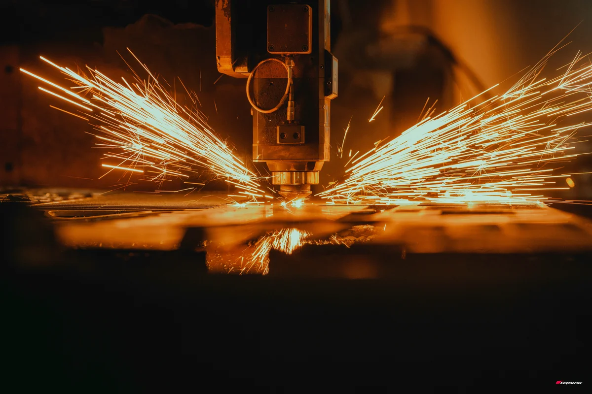 Debitare laser CNC în acțiune — scântei intense portocalii la tăierea tablei de oțel